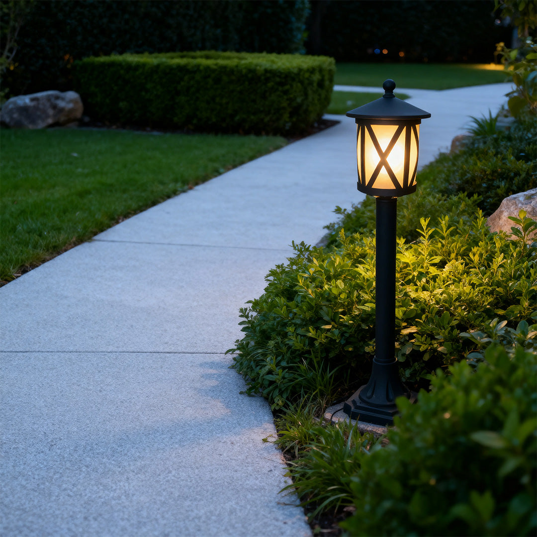 Contemporary garden bollard light illuminating concrete walkway through manicured lawn at twilight