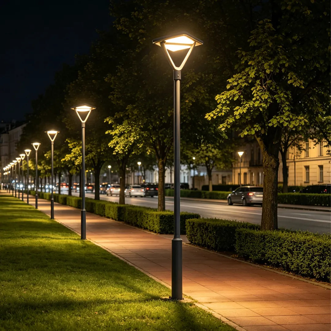 Contemporary garden street lights lining a sidewalk and grassy boulevard in the evening.
