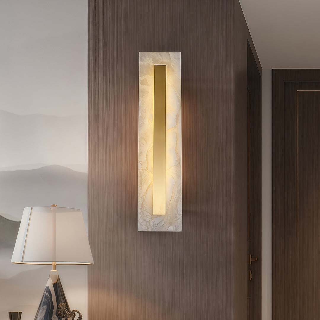 Contemporary gold wall light with glass shade chandelier aesthetic providing warm accent lighting in neutral-toned bedroom with wood accents.