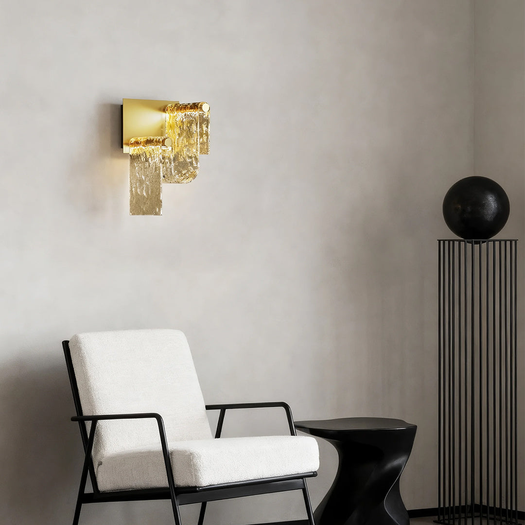 Contemporary gold wall light brightening minimalist grey bedroom with black accent chair