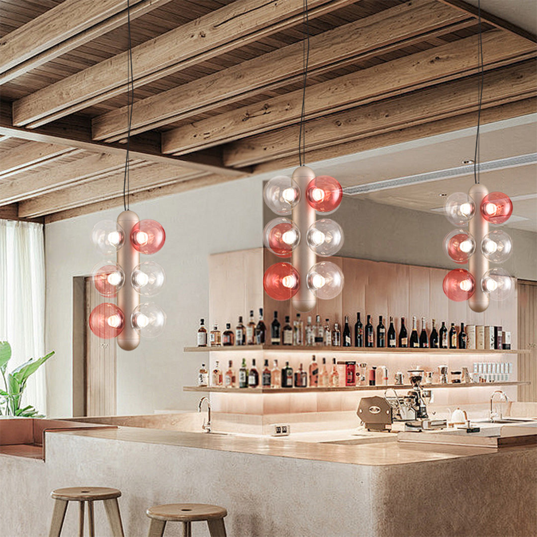 Contemporary hanging light fixture featuring cascading spherical glass shades in rose and clear tones
