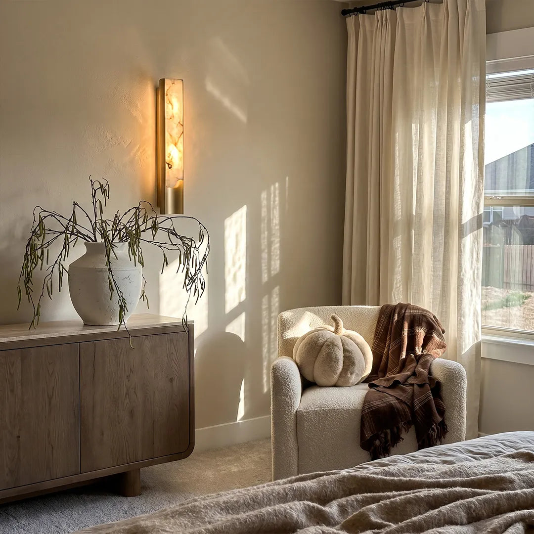 Contemporary indoor wall lights illuminating a cozy reading corner with a cabinet and armchair.