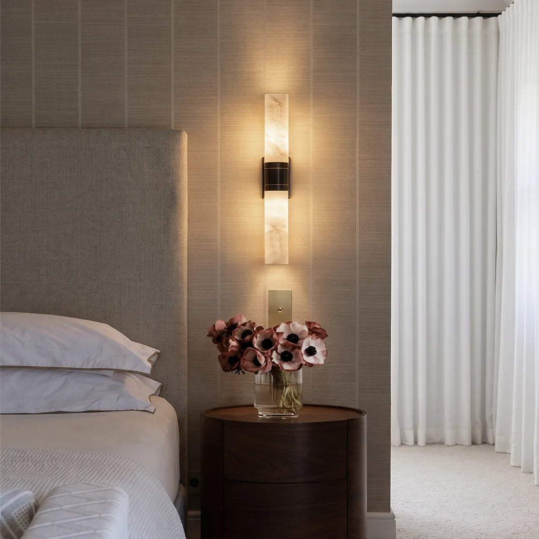 Contemporary indoor wall sconces mounted beside a bed with a slim stone-look shade and warm ambient glow.