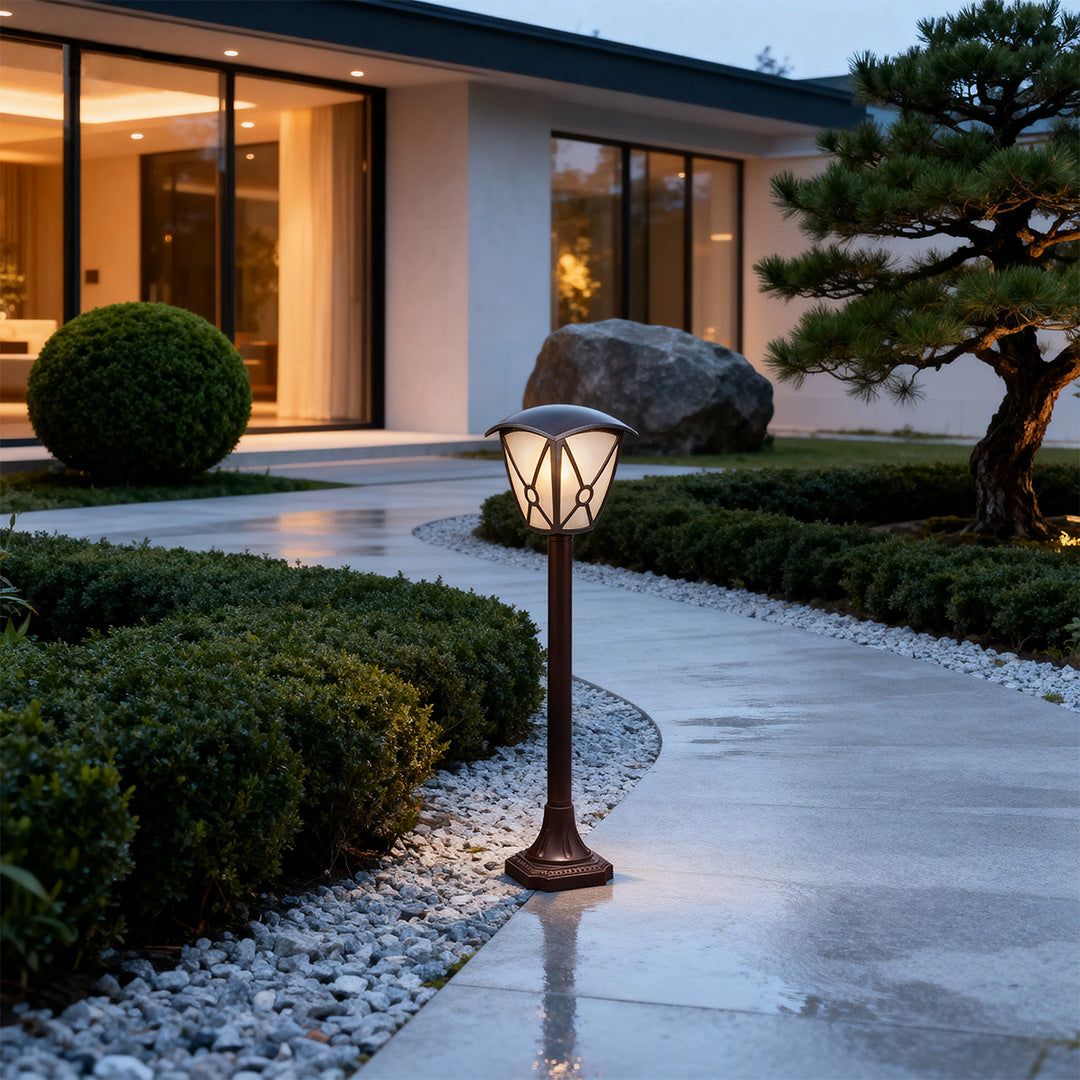 Contemporary LED fence bollard light glowing warmly on driveway near modern architecture in evening