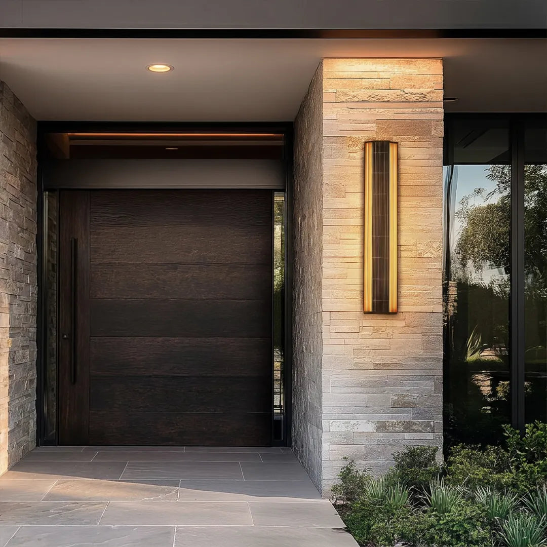 Contemporary LED wall light installed beside a modern front door on a stone entry facade.