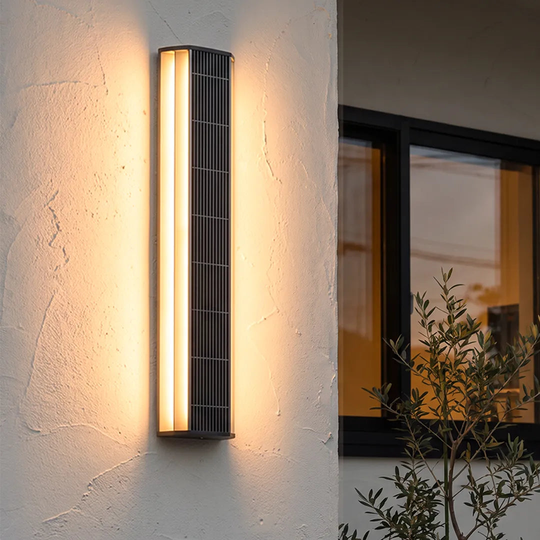 Contemporary LED wall light mounted on a textured exterior wall beside a glass door, creating a soft warm glow.