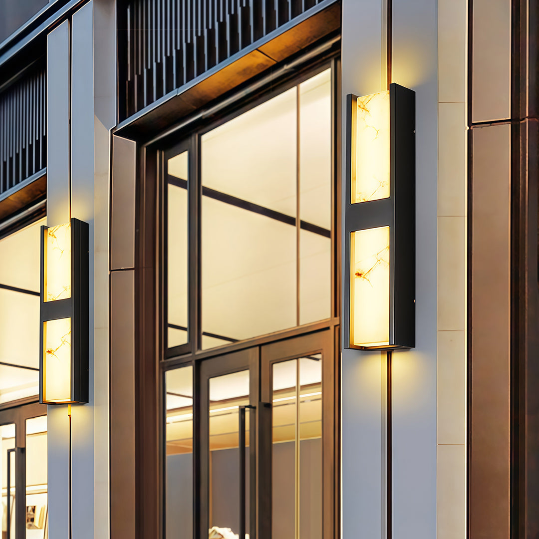 Contemporary LED wall sconce light fixtures with glass shade chandelier aesthetic flanking modern entrance door with warm glow.