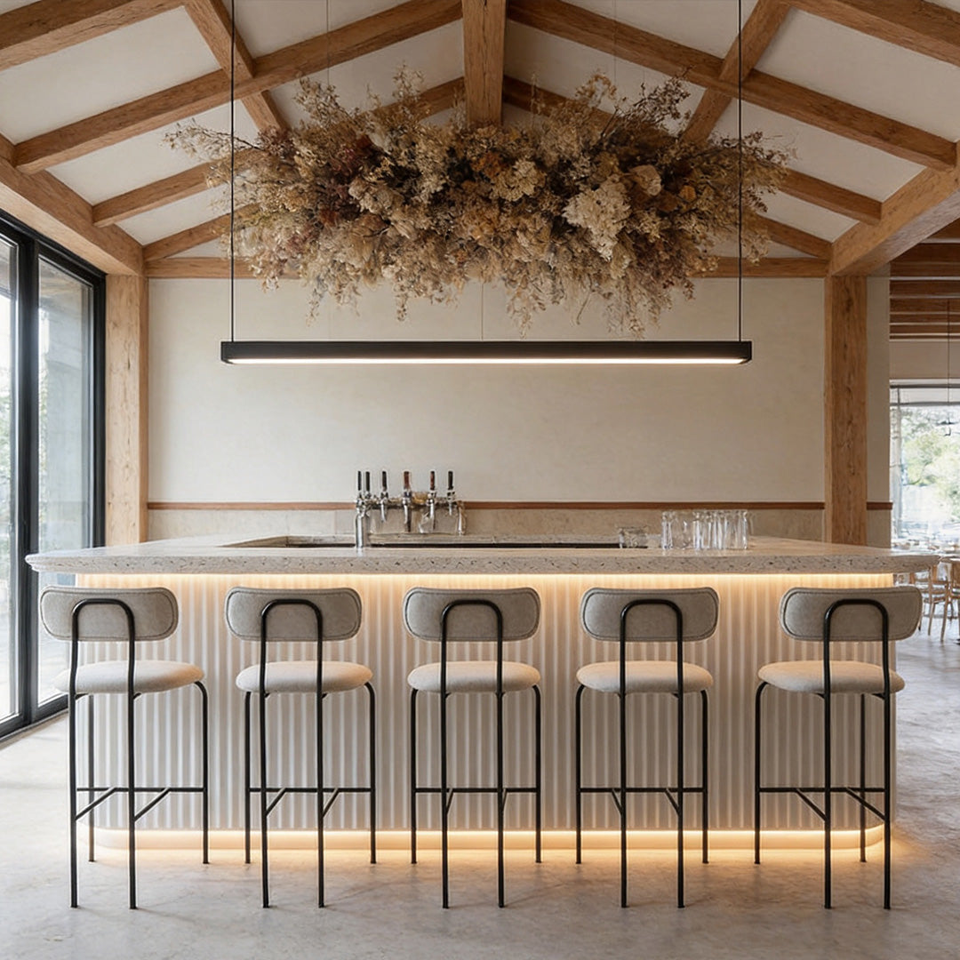 Contemporary linear pendant light fixtures above a stylish café bar seating area.