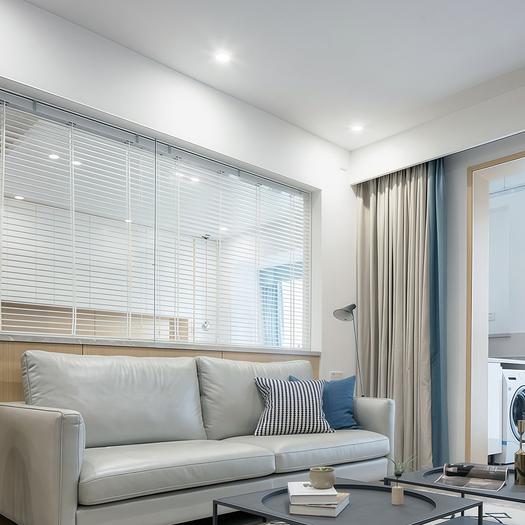 Bright contemporary living space with a white mesh divider and modern spotlights providing clean illumination.