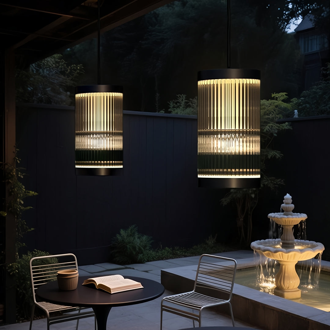 Contemporary outdoor pendant light fixture illuminating an outdoor lounge area with warm ambient glow.