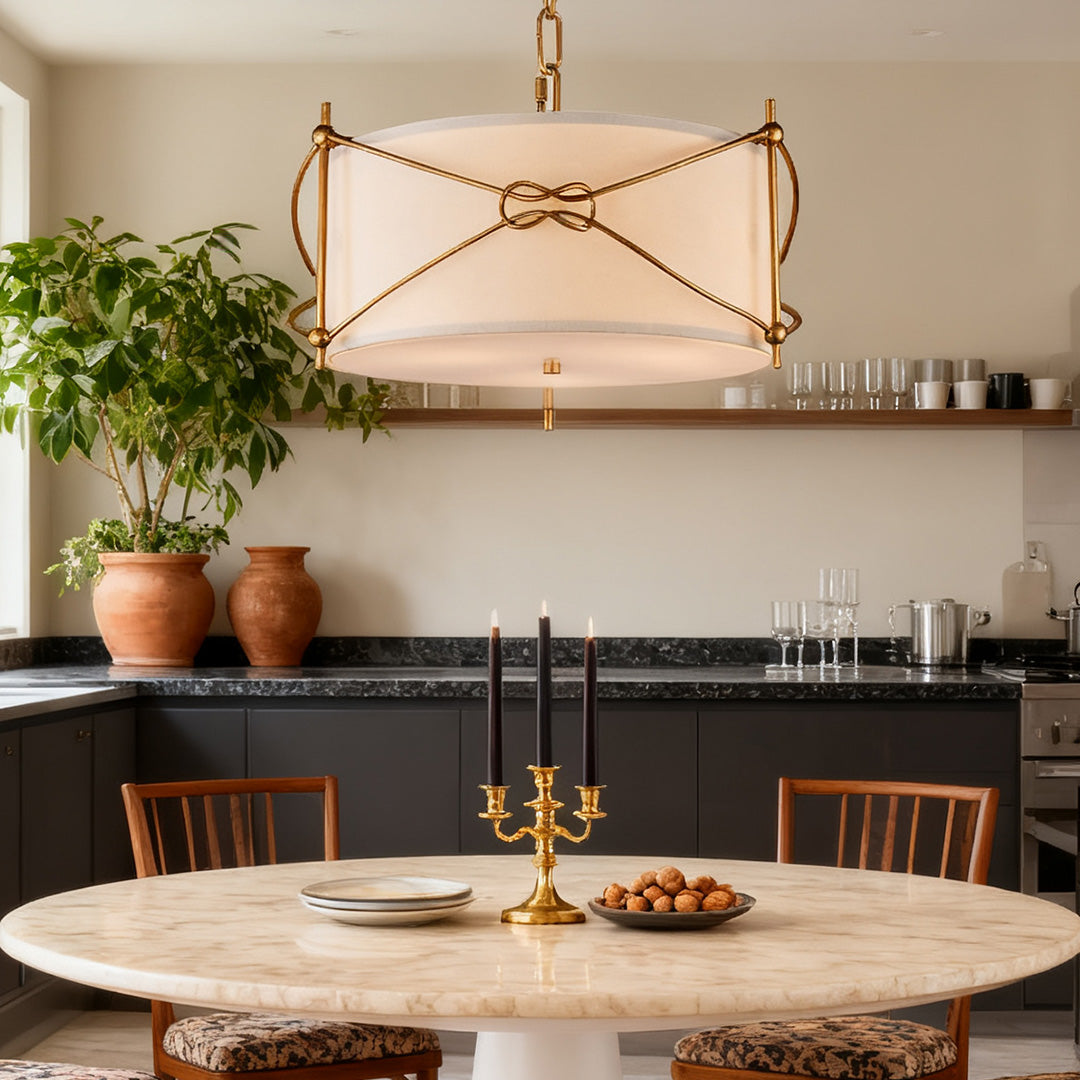 Contemporary kitchen area with a white drum pendant light hanging over a round marble table and accented by dark cabinetry and clay pots.