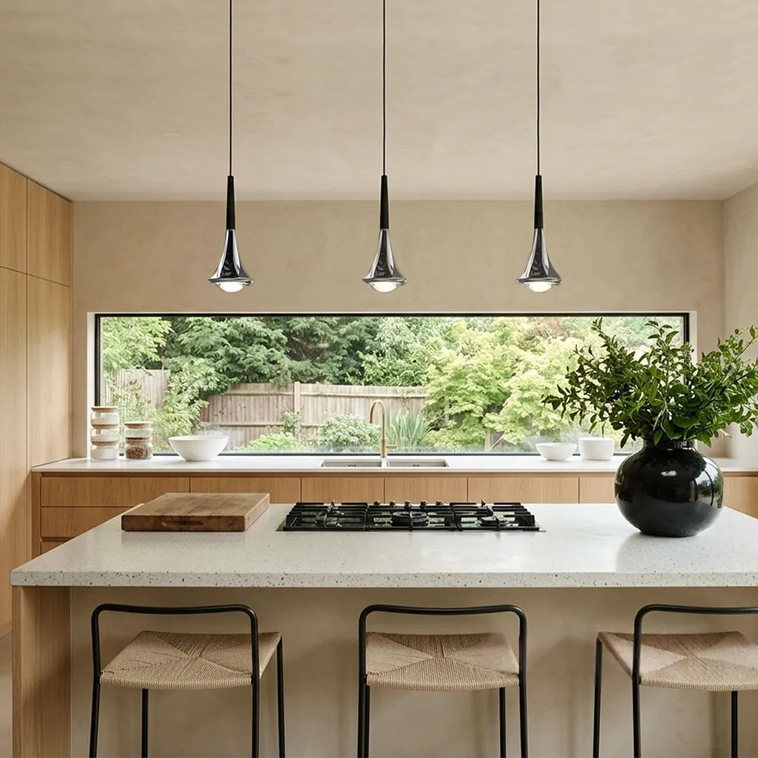 Contemporary mini pendant lights aligned above a bright kitchen island with a large picture window and woven stools.