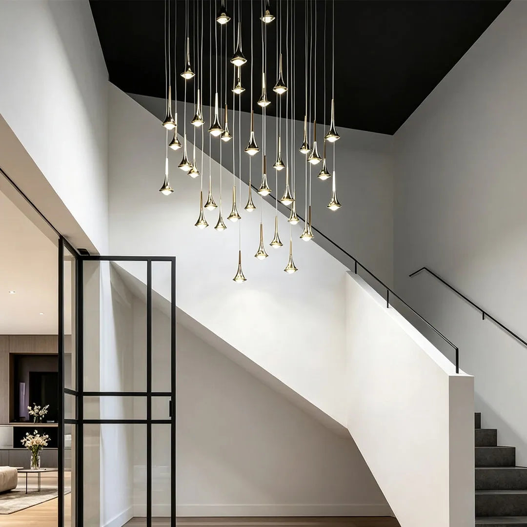Contemporary mini pendant lights arranged in a dramatic cluster over a modern staircase in a double-height interior.