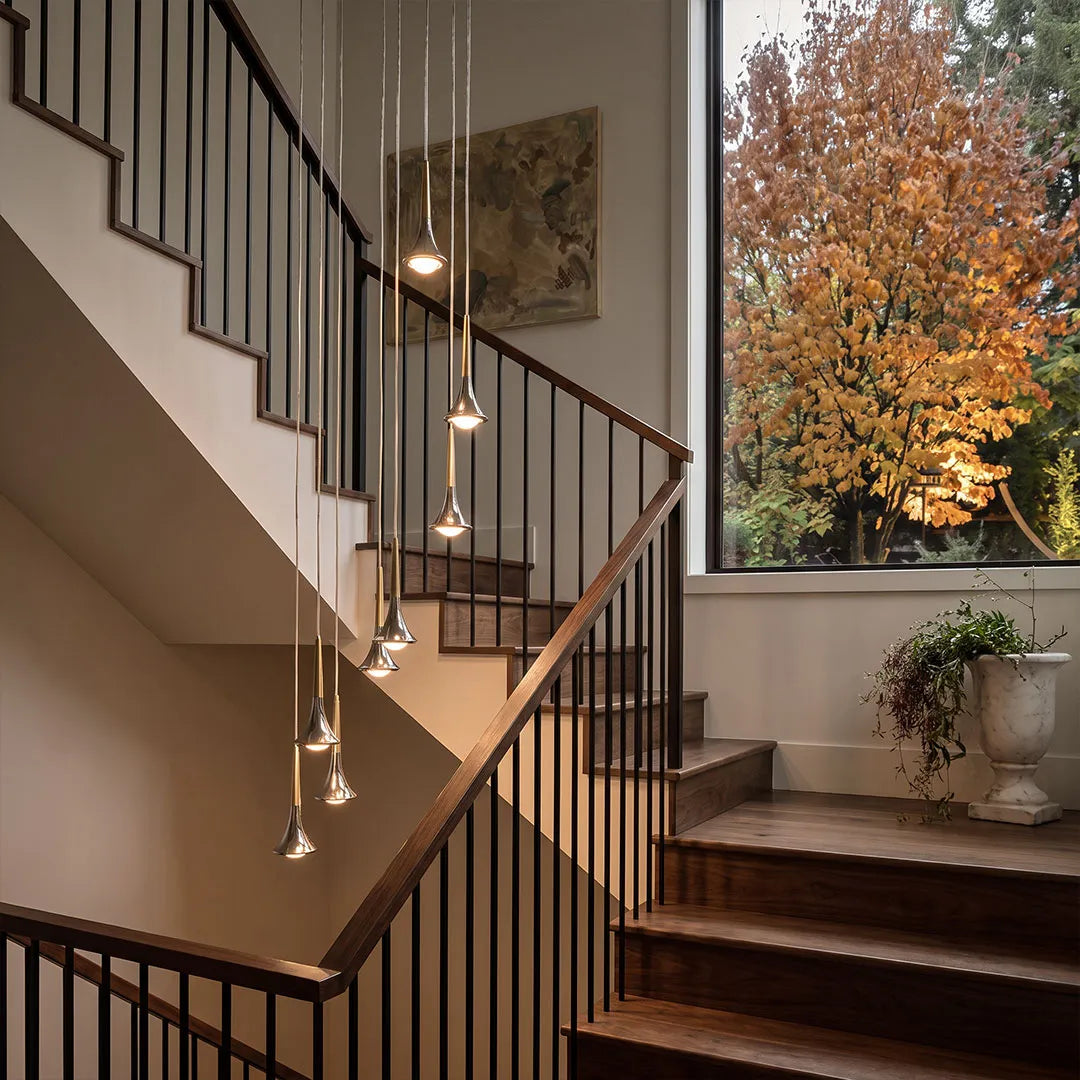 Contemporary mini pendant lights suspended along a staircase to create a modern cascading lighting display.