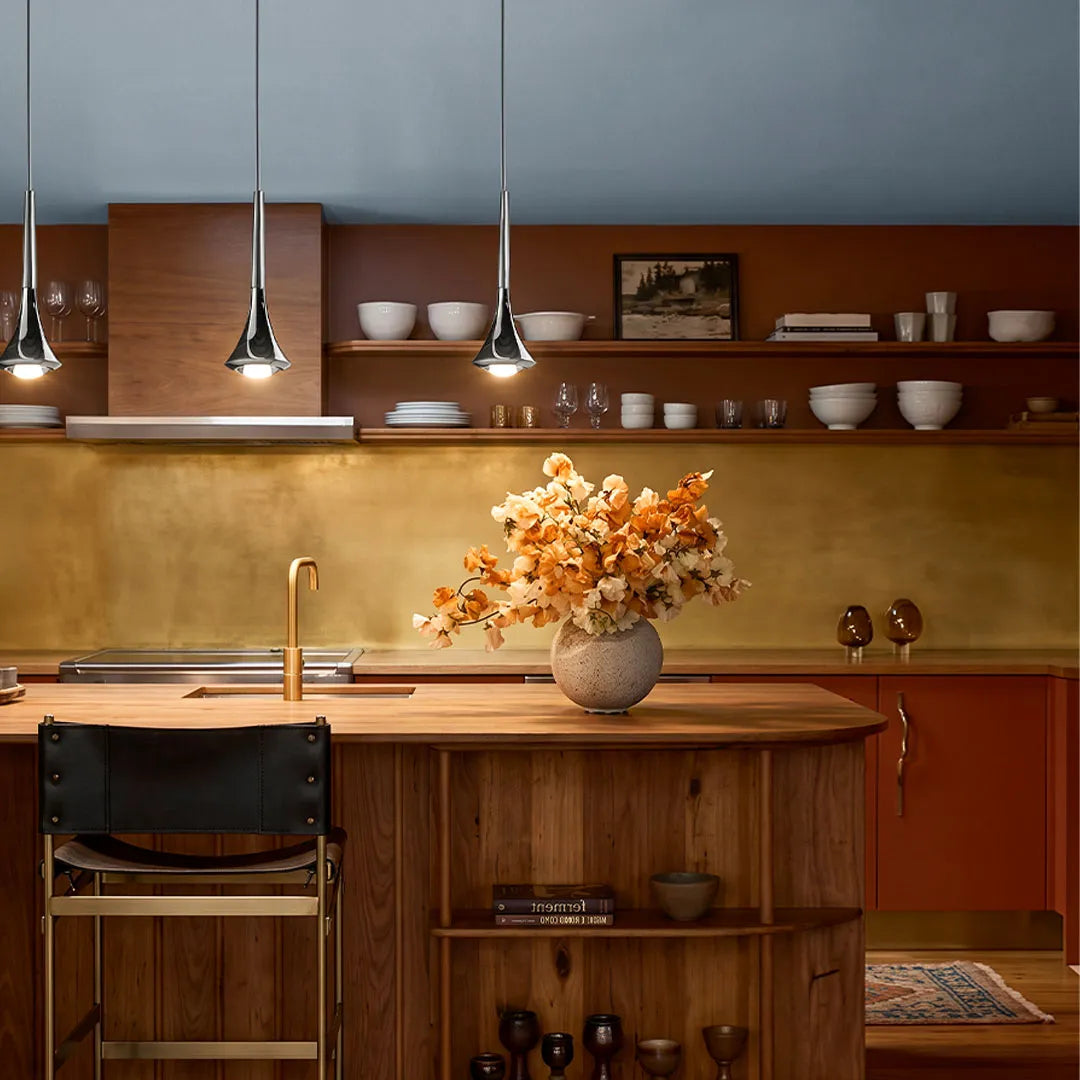 Contemporary mini pendant lights hanging above a warm wood kitchen island with open shelving and soft ambient lighting.