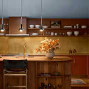Contemporary mini pendant lights hanging above a warm wood kitchen island with open shelving and soft ambient lighting.
