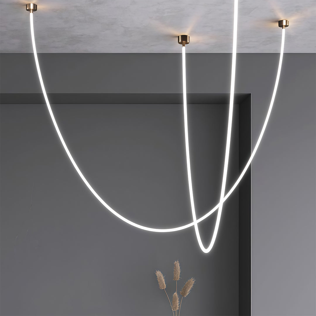 Contemporary neon pendant lights suspended from grey ceiling with person in foreground for scale.