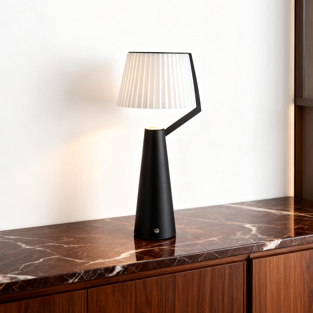 Contemporary Nordic table lamp with a contrasting black stem and white pleated shade on a marble countertop.