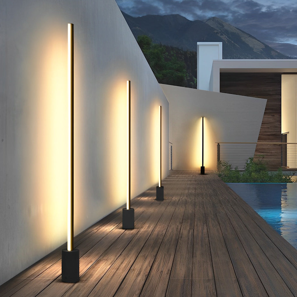 Contemporary outdoor floor lamps casting warm light along a wall side walkway.