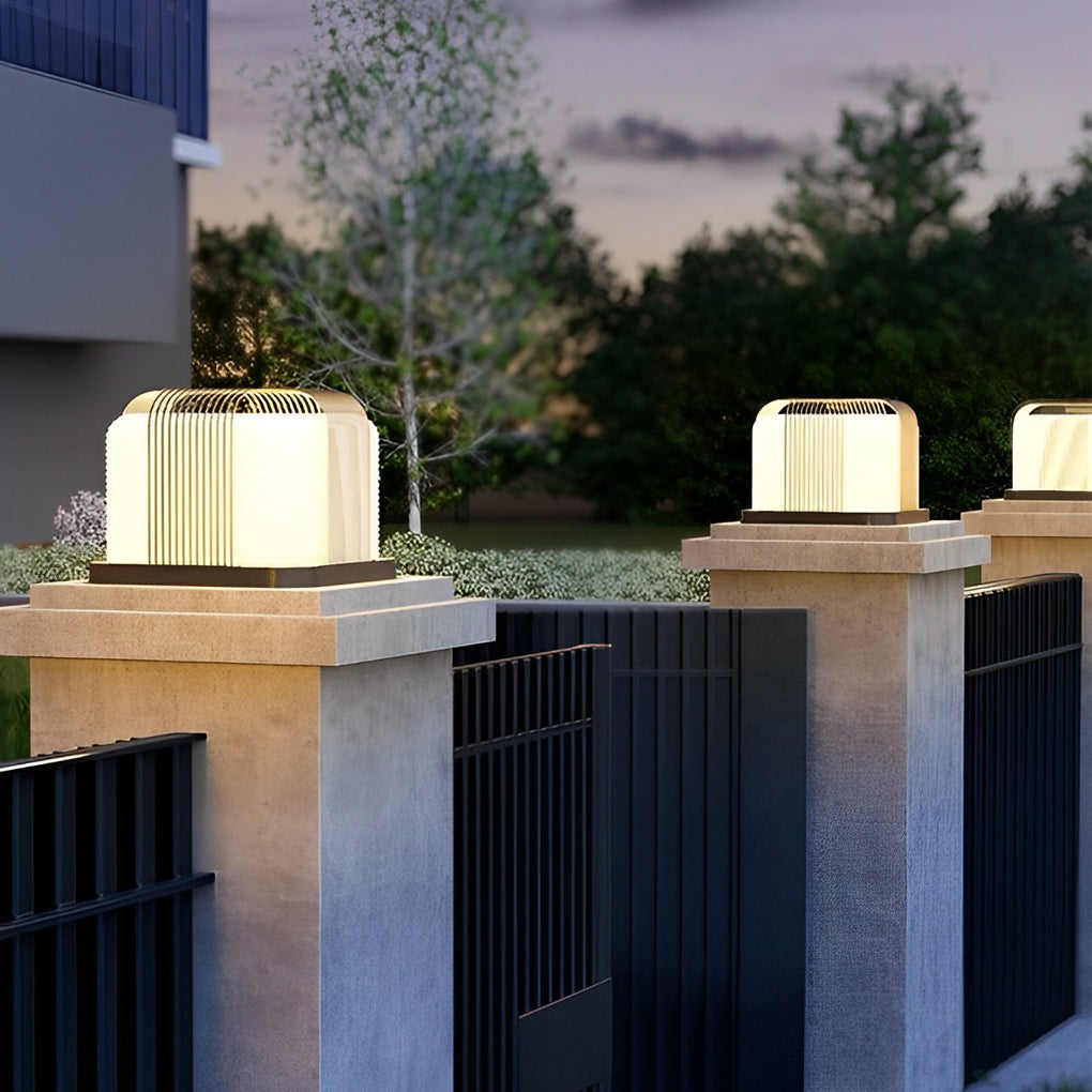 Contemporary outdoor pillar lights with a black finish, providing ambient light near a fence.