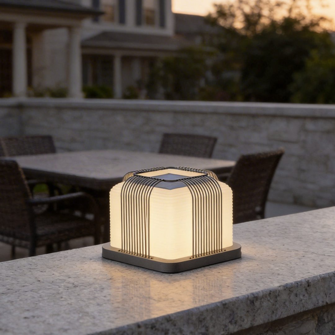 Contemporary outdoor pillar lights with a sleek curved design, illuminating a modern patio table.