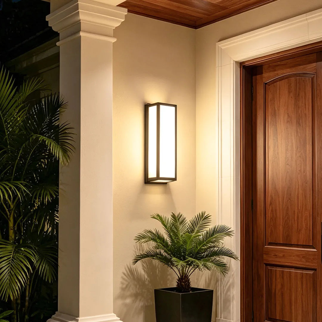 Contemporary outdoor wall light mounted next to a wooden front door under a covered porch.