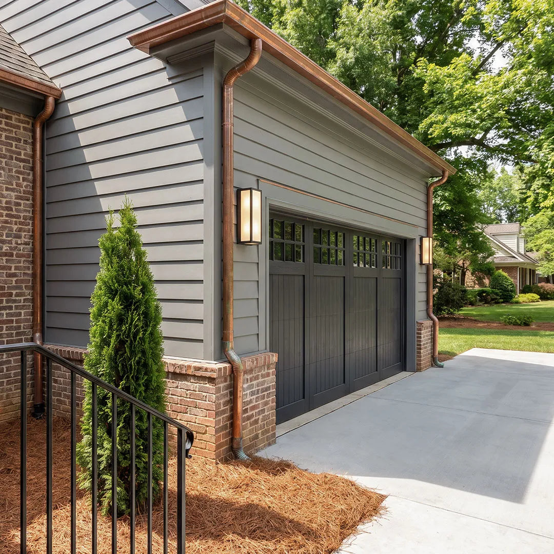 Contemporary outdoor wall light installed beside a garage door on a modern suburban home exterior.