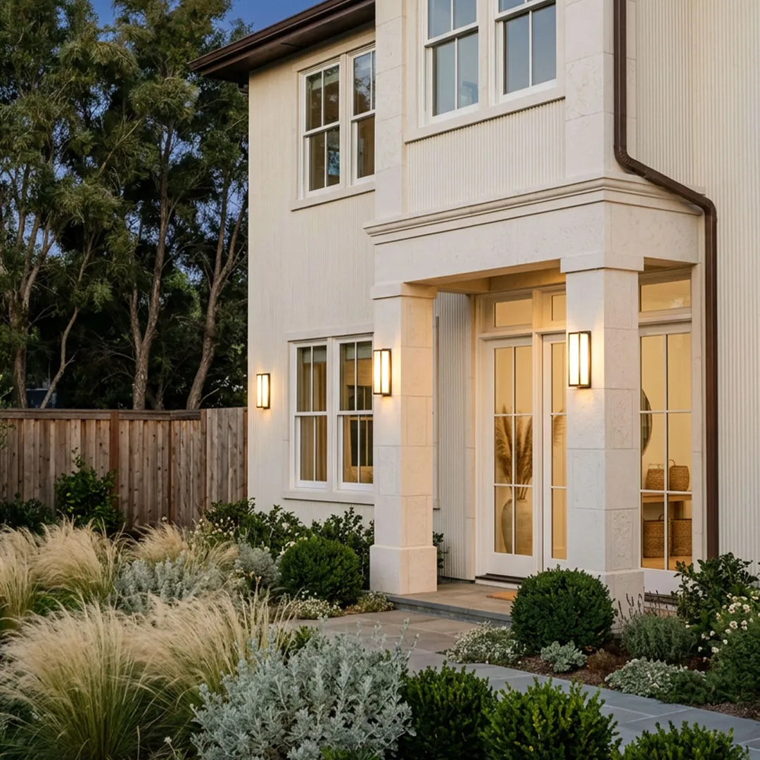 Contemporary outdoor wall light illuminating the exterior of a two-story home with a landscaped front yard.