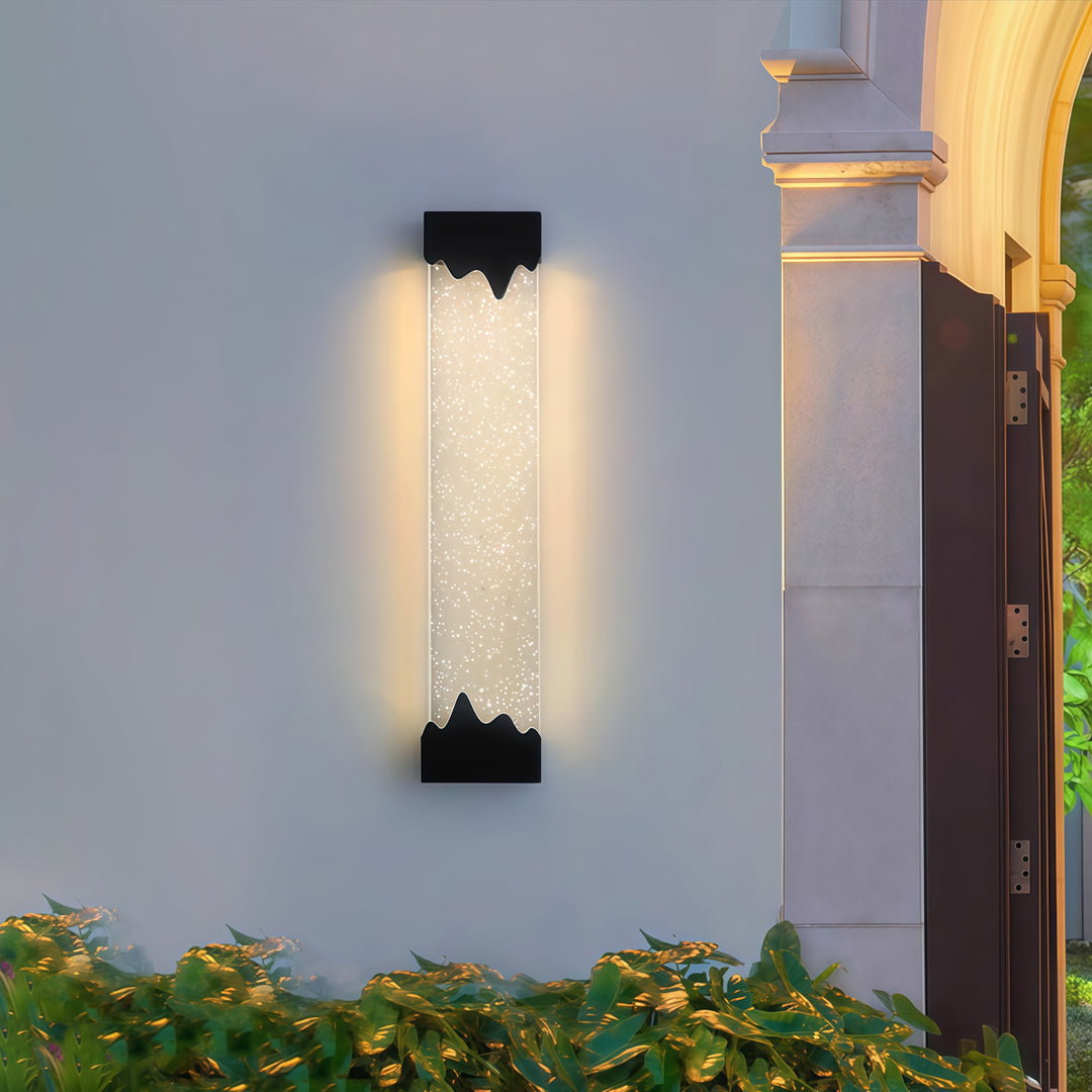 Contemporary outdoor wall lighting black linear fixture illuminating gray exterior wall with landscaping at dusk