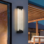 Contemporary outdoor wall lighting black linear sconce on textured wall beside modern patio with warm evening glow