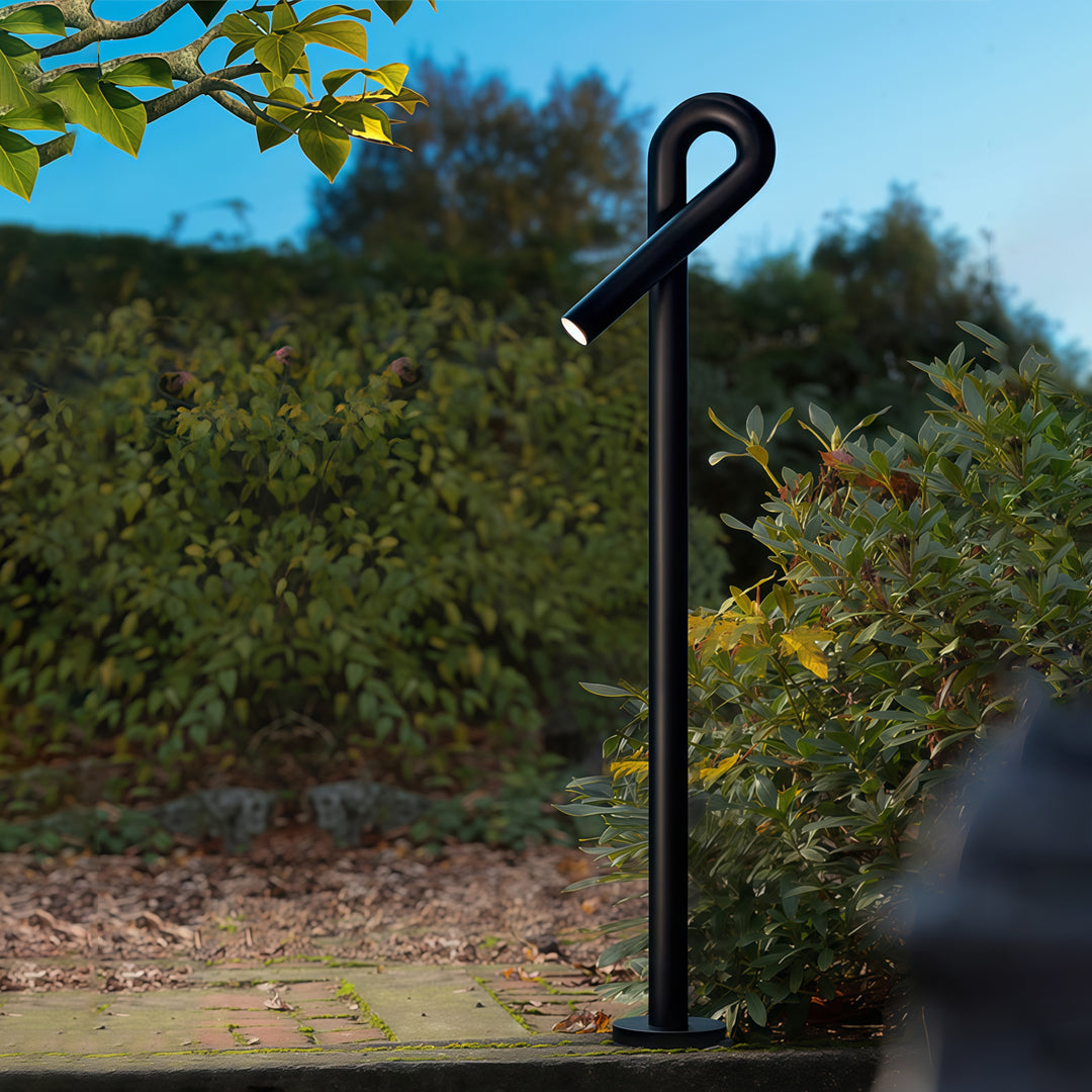 Contemporary outdoor wall lighting bollard light post in landscaped yard with blue sky and green foliage