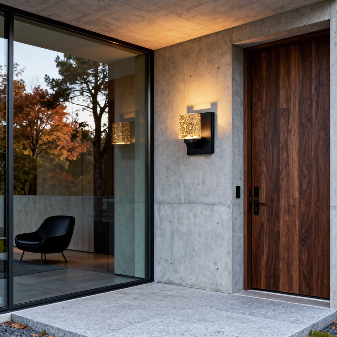 Contemporary outdoor wall lighting crystal fixture illuminating modern entrance with wooden door and concrete walls