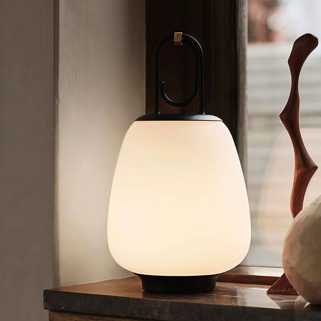 Contemporary outdoor wall lighting portable table lamp creating warm ambient glow on dark wooden surface indoors