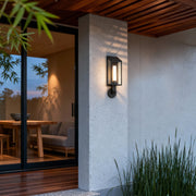 Contemporary outdoor wall mount light fixture mounted on a stone exterior wall, providing warm architectural lighting.