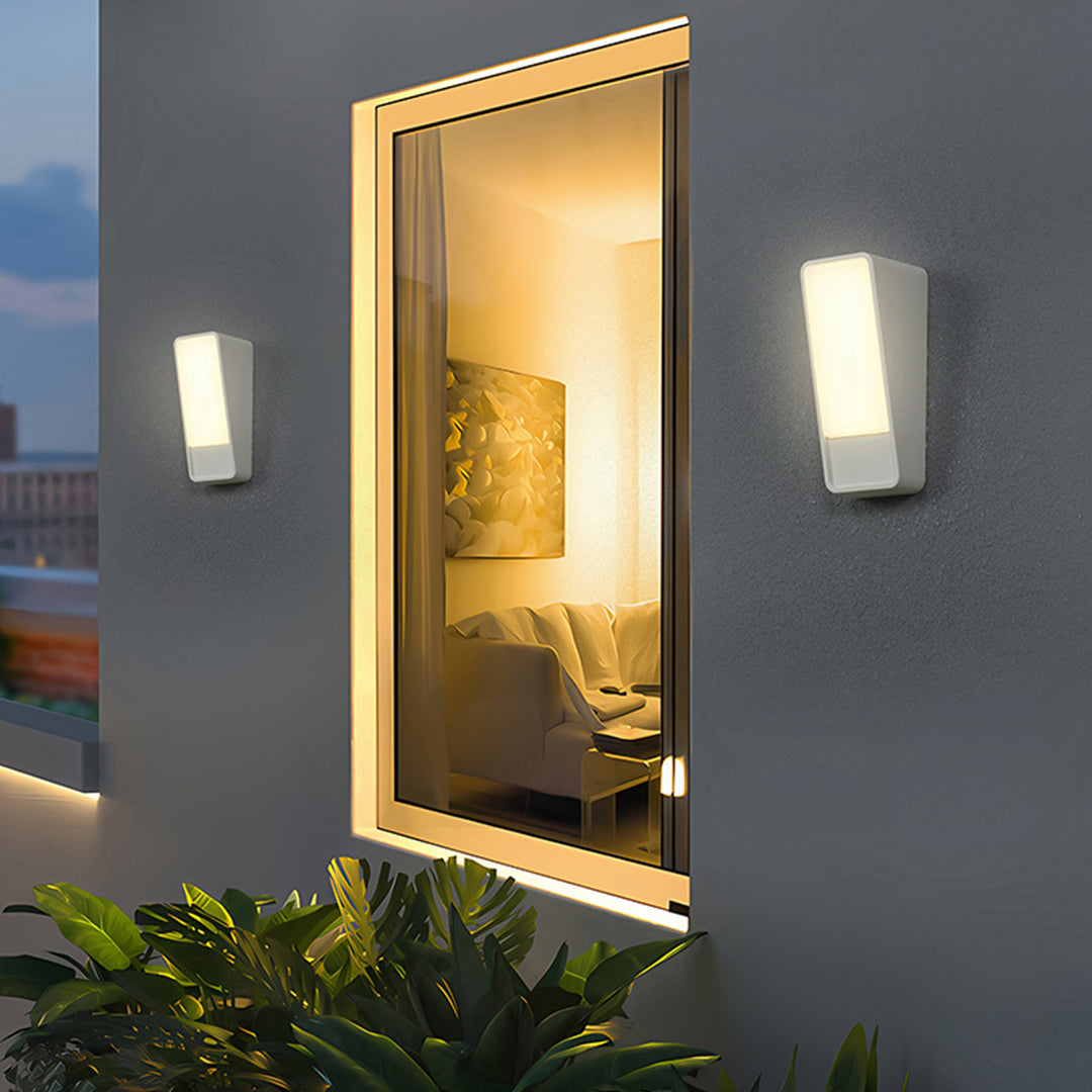 Contemporary outdoor wall sconces flanking illuminated entrance door with warm lighting