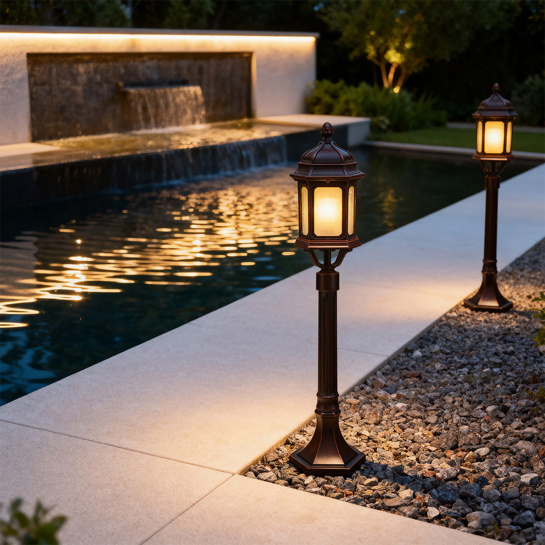 Contemporary path post light casting bright glow along modern paved walkway beside reflective pool