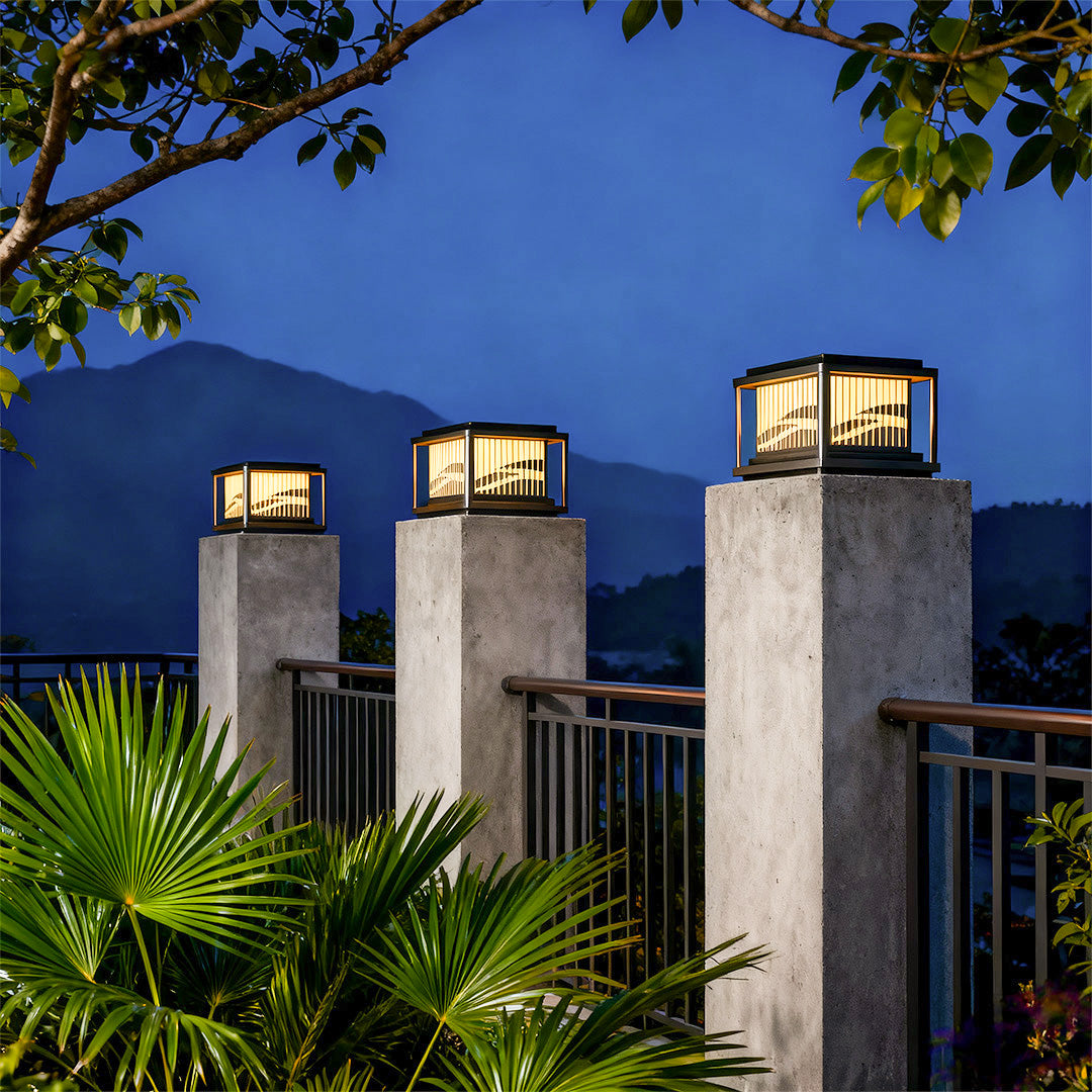 Contemporary pillar lights illuminating residential entrance with tropical plants and modern architecture at night.