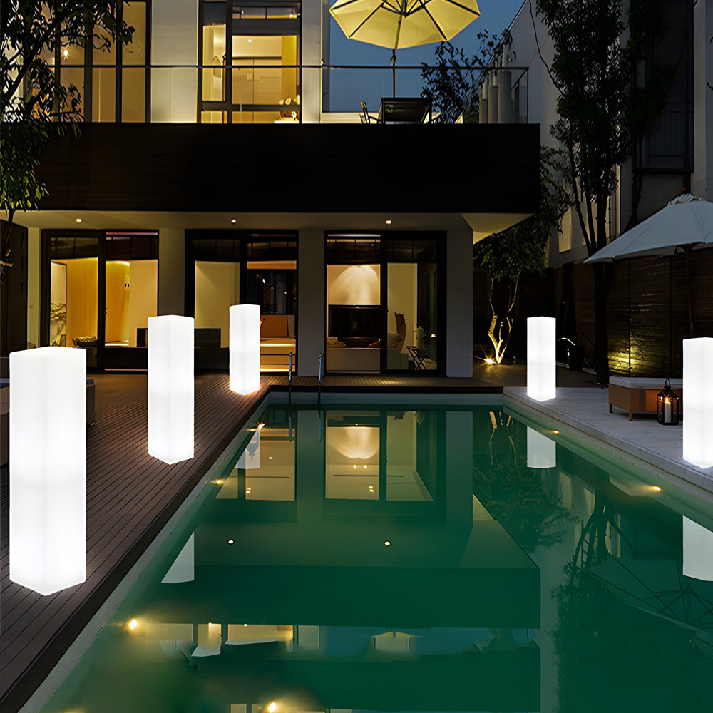 Sleek white column lights positioned beside swimming pool in upscale residential backyard setting