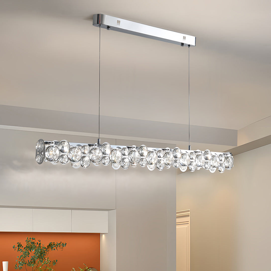 Contemporary silver pendant light showcasing sparkling crystal accents and a polished chrome canopy against a light gray wall.