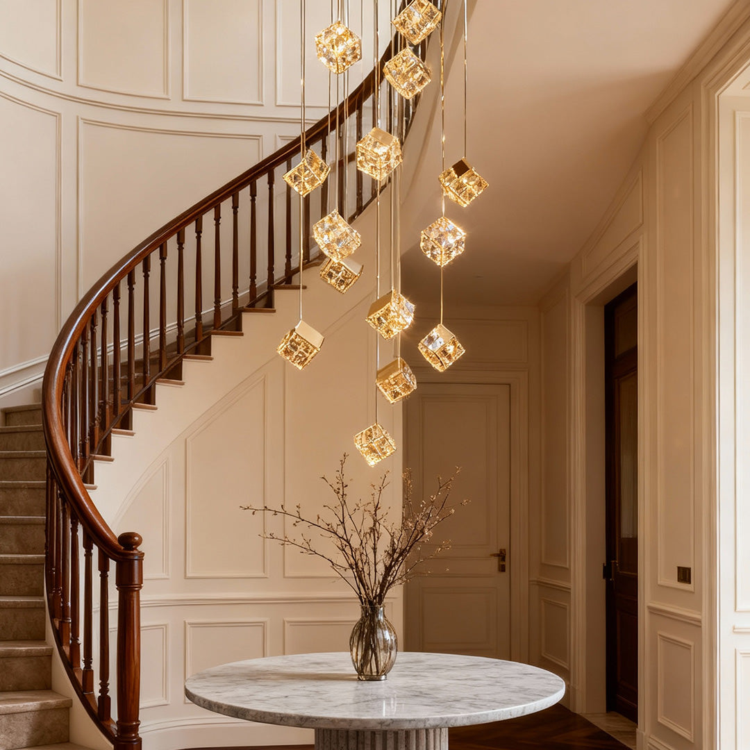 Contemporary gold stairs chandelier glowing above curved wall and bench.