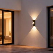 Contemporary up down wall lights illuminating a modern house entrance with warm directional glow.