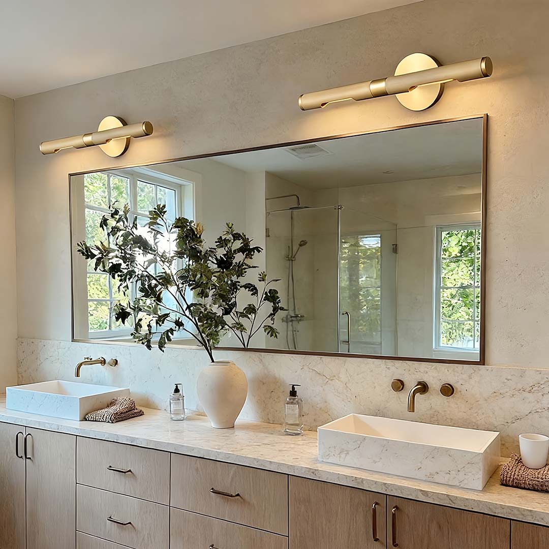 Contemporary vanity light bar with a close-up of its gold frame and warm light above a vanity.