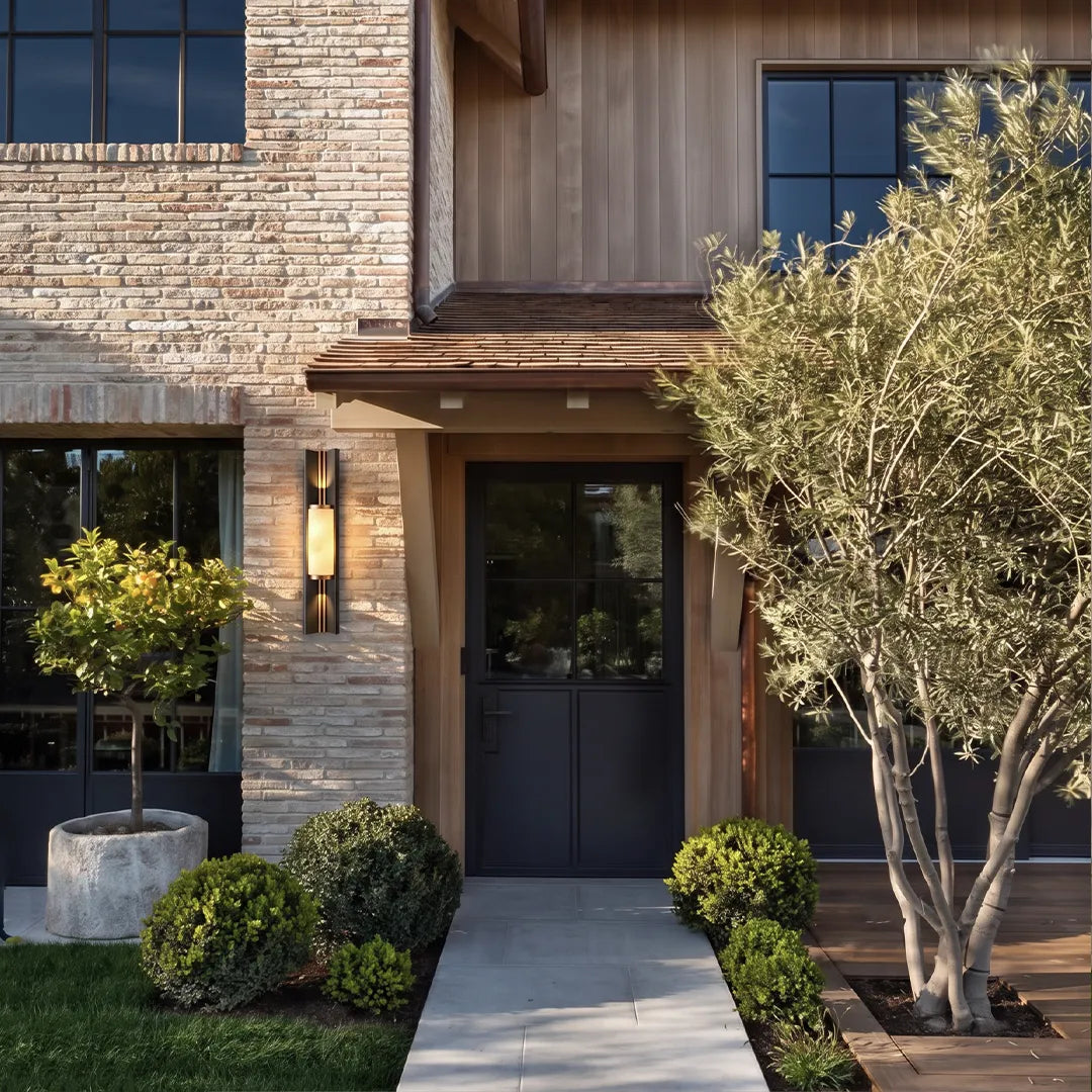 Contemporary wall light fixtures providing warm entry lighting beside a modern dark front door.