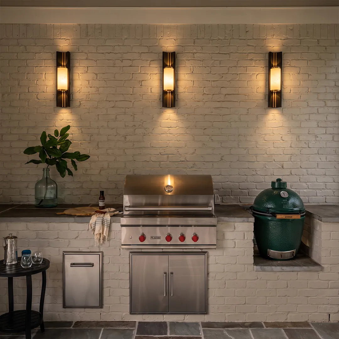 Contemporary wall light fixtures arranged above an outdoor grill for even patio task lighting.