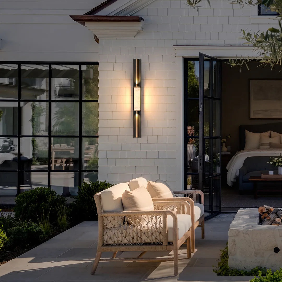 Contemporary wall light fixtures mounted beside glass doors to illuminate a covered outdoor seating area.