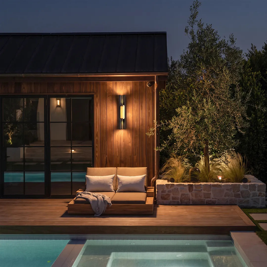 Contemporary wall light fixtures illuminating a modern poolside patio with warm ambient light.