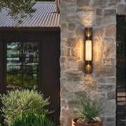 Contemporary wall light fixtures mounted on a stone exterior wall with warm vertical illumination.