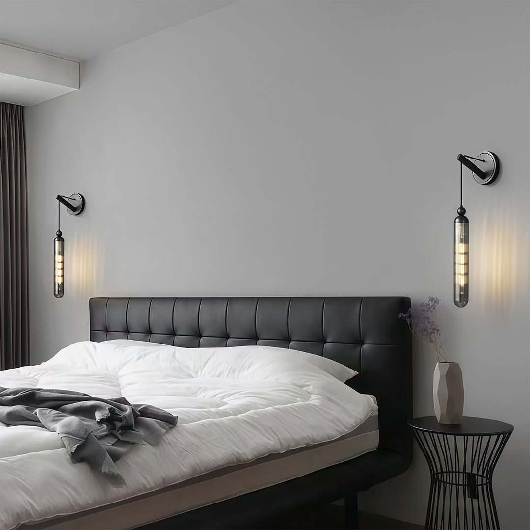 Contemporary wall mount pendant light with glass shade chandelier aesthetic flanking modern bed in symmetrical arrangement.