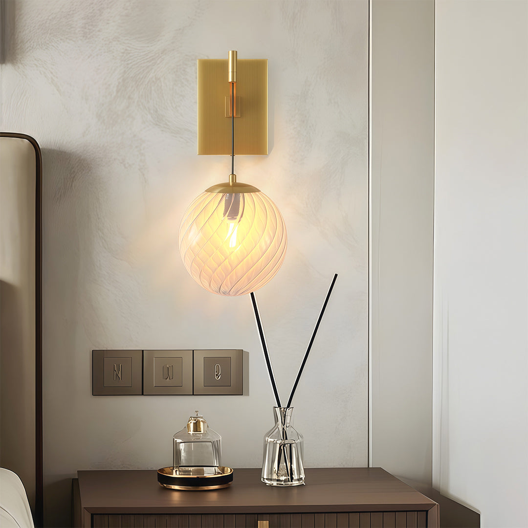 Contemporary wall mounted pendant light with glass shade chandelier aesthetic illuminating bedroom nightstand with warm light.