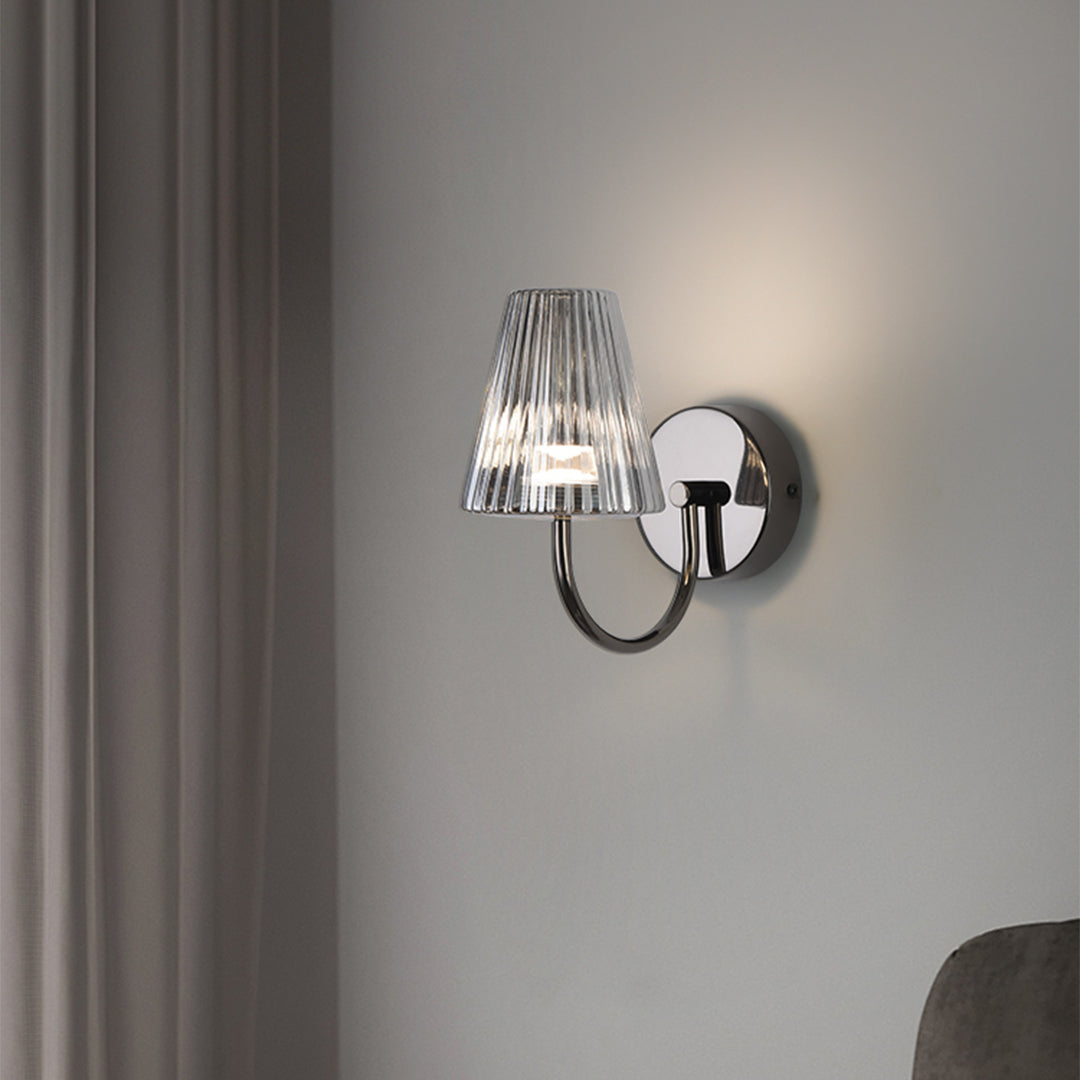 Contemporary wall sconce illuminated in minimalist bedroom setting with clean white walls